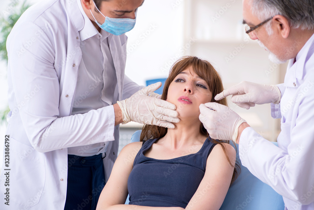 Fototapeta premium Two male doctors and young woman in plastic surgery concept