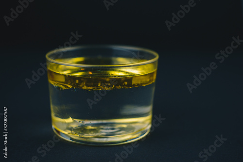 Glass cup with water and oil inside, water and oil perfectly separated. Isolated on a black background.Abstract concept.Copy space