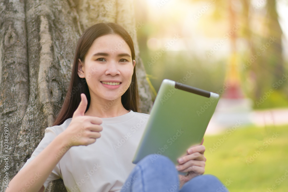 Fototapeta premium Woman use tablet sitting at city park happiness in day time online internet technology