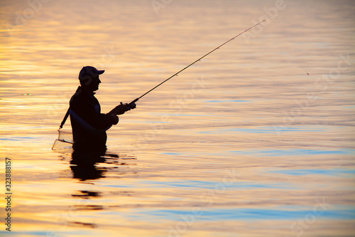 unrecognizable silhouette of man fishing at sunset