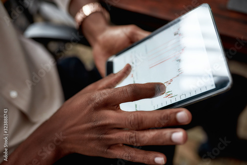 Nurture the future. Close up shot of hands holding tablet pc. Trader is using touch screen tablet for analyzing stock market chart  while working in the office