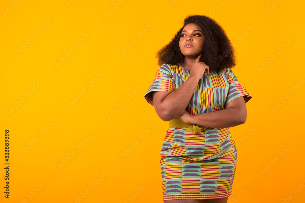 Young beautiful african american girl with an afro hairstyle. Portrait on yellow background with copyspace. Young beautiful african american girl with an afro hairstyle. Portrait on yellow background with copyspace.