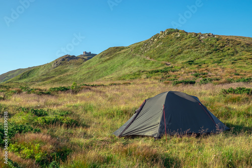 Green tourist tent in camp among meadow in the mountain.Nature background