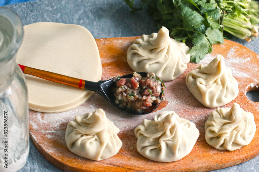 georgian dumplings khinkali with meat filling cilantro, coriander on kitchen board close up photo with human hand georgian dumplings khinkali with meat filling cilantro, coriander on kitchen board close up photo with human hand
