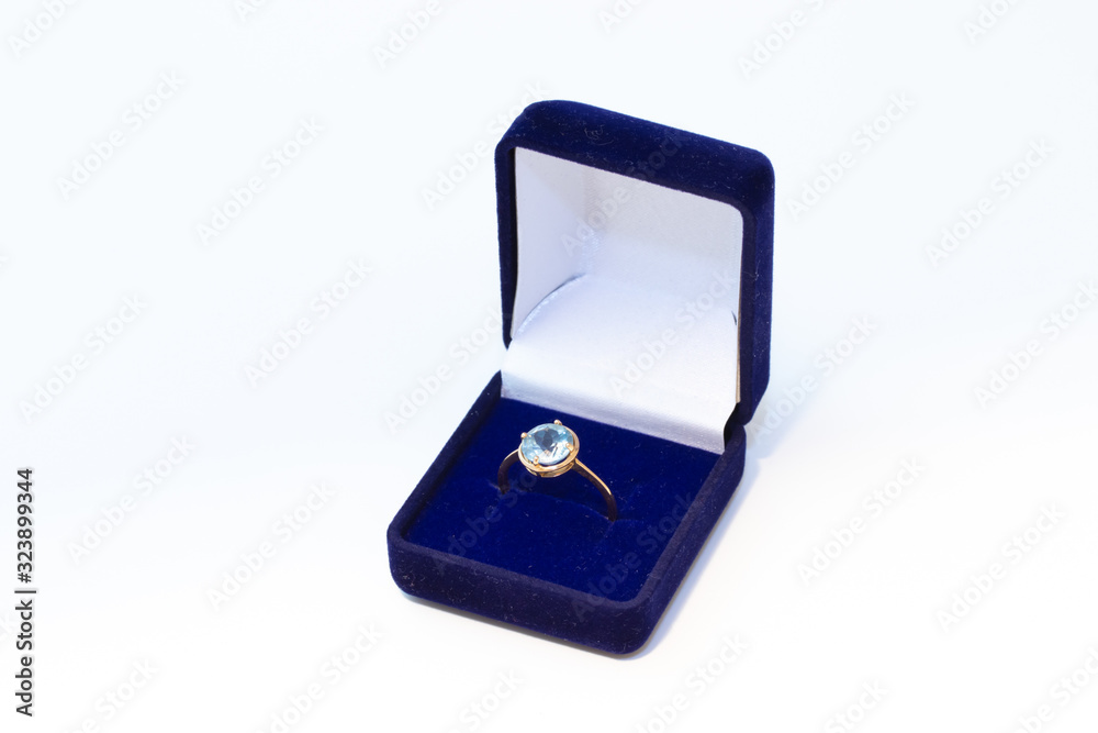 Golden ring with gemstone in a blue jewelry box on white background Golden ring with gemstone in a blue jewelry box on white background