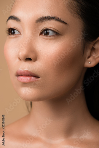 beautiful naked asian girl looking away isolated on beige