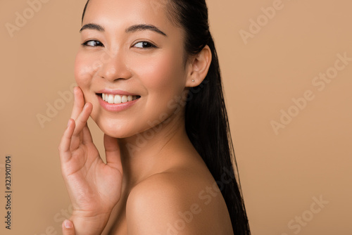 smiling beautiful naked asian girl looking away isolated on beige