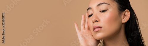 beautiful asian girl touching face isolated on beige, panoramic shot