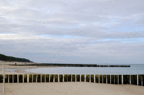 Breakwaters on the beach and beautiful blue sky with clouds in Dziwnowek / Poland on the Baltic Sea.