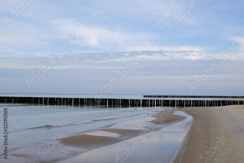 Breakwaters on the beach and beautiful blue sky with clouds in Dziwnowek   Poland on the Baltic Sea.