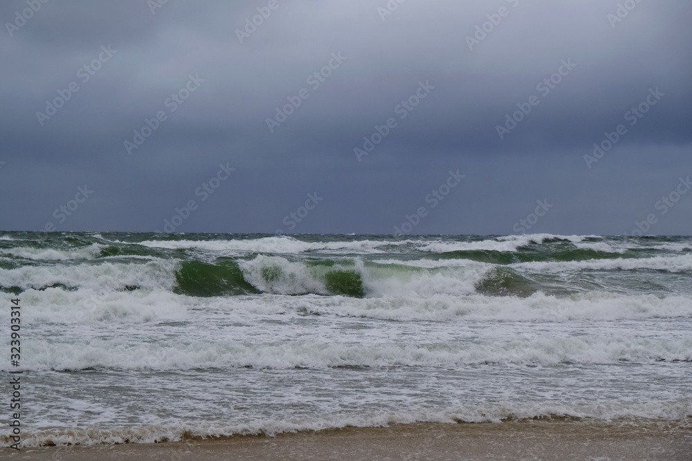 Rough sea with waves during autumn stormy weather. Black heavy clouds in the sky. Baltic Sea, Dziwnowek, Poland