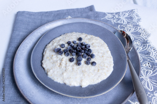 Oat kasha with blackberry in gray plate with spoon on textile vintage cover photo