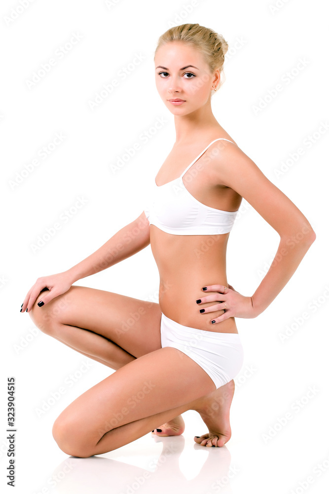 Elegant Slender young girl fitness model in white lingerie posing in the studio on a white background. Concept cosmetology and fitness. Advertising space