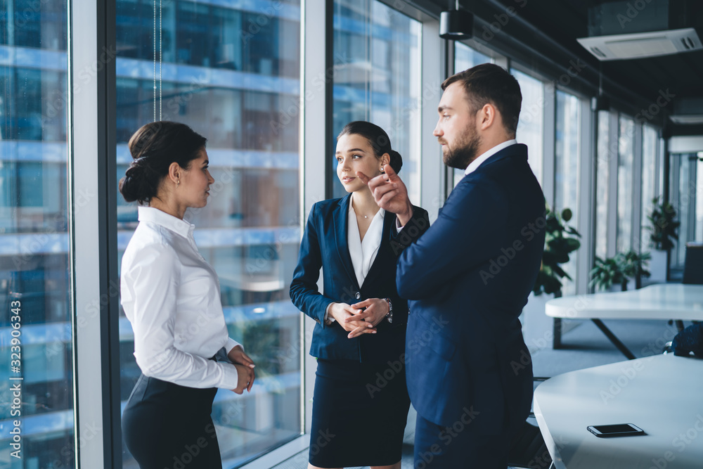 Positive colleagues having conversation while standing in office lobby Positive colleagues having conversation while standing in office lobby