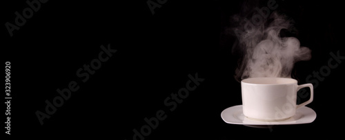 White coffee cup on plate with smoke isolated on black background in studio With copy space.