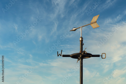 Old rusty weather vane against a cloudy blue sky