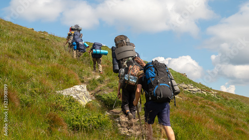 Tourists with hiking backpacks walk along a mountain trail. Background illustrating a healthy lifestyle.