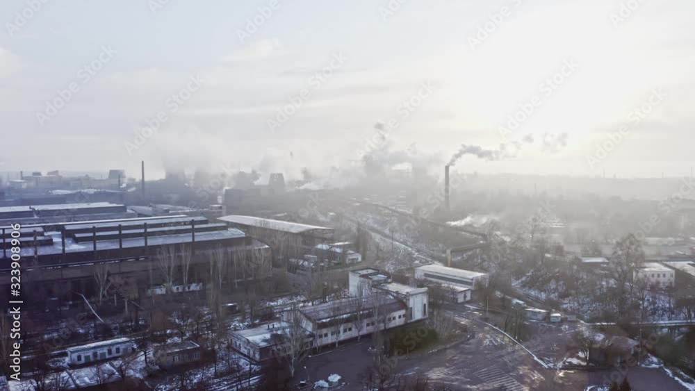 Aerial view. Emission to atmosphere from industrial pipes metallurgic factory in winter. Smokestack pipes at plant shoot with drone. Aerial drone footage of steel factory pipes during sunrise time. Aerial view. Emission to atmosphere from industrial pipes metallurgic factory in winter. Smokestack pipes at plant shoot with drone. Aerial drone footage of steel factory pipes during sunrise time.