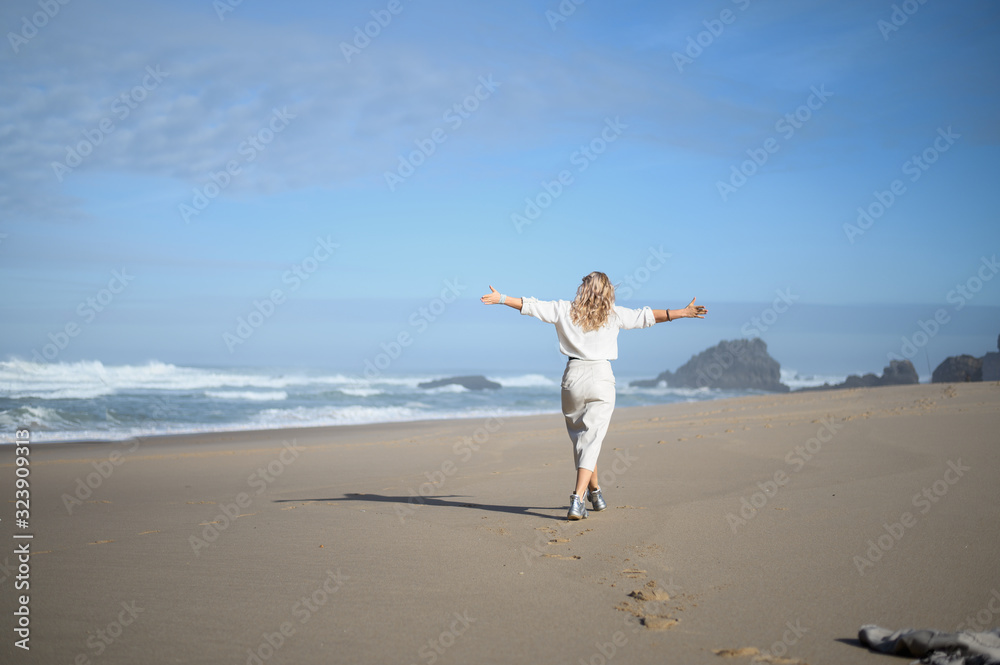 Blonde walks on the beach with outstretched arms. Vacation. Blonde walks on the beach with outstretched arms. Vacation.