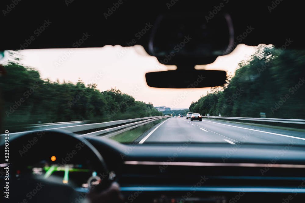Selective focus on street highway roadway fro crossing by comfortable travel car, male driver wheeling transport for getting to destination over interstate motorway, executive motorized vehicle