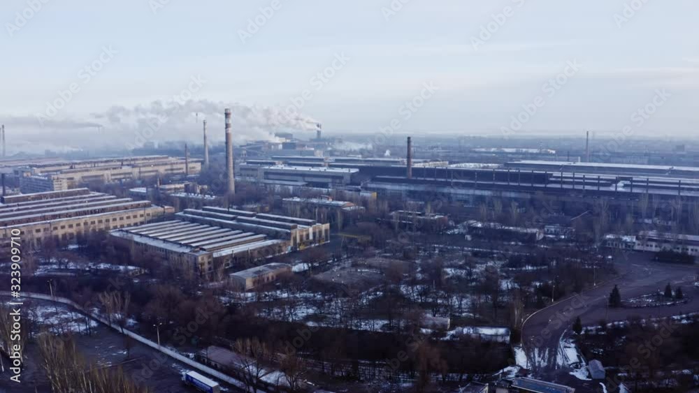 Aerial view. Emission to atmosphere from industrial pipes metallurgic factory in winter. Smokestack pipes at plant shoot with drone. Aerial drone footage of steel factory pipes during sunrise time. Aerial view. Emission to atmosphere from industrial pipes metallurgic factory in winter. Smokestack pipes at plant shoot with drone. Aerial drone footage of steel factory pipes during sunrise time.
