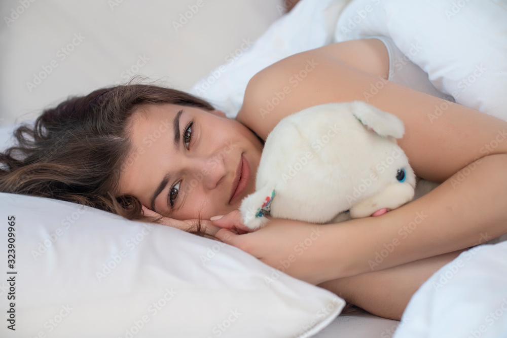 Young pretty woman in bed hugging a teddy bear. Young pretty woman in bed hugging a teddy bear.