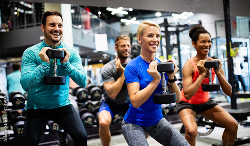 Group of young happy fit people doing exercises in gym photo