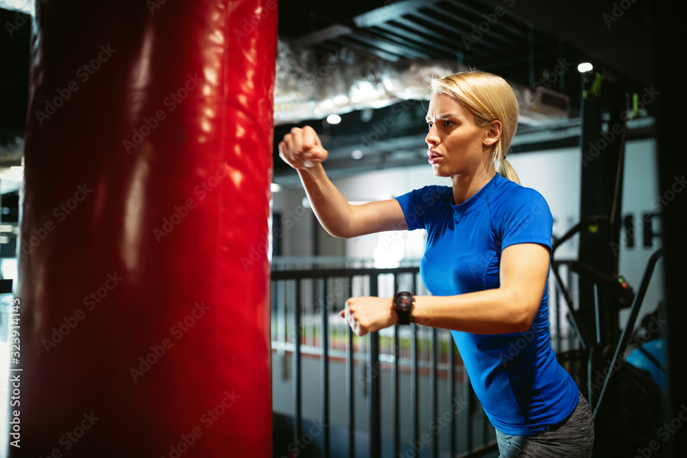 Boxing training woman with punching kicking bag in gym