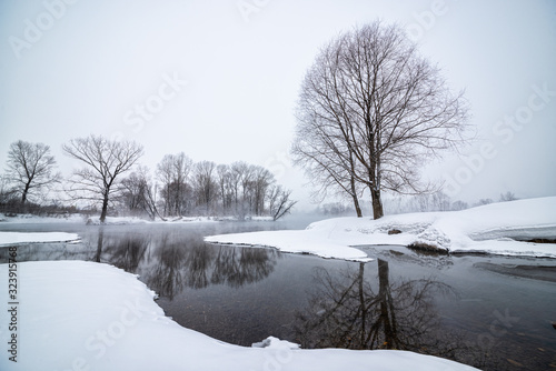 Snowy frozen landscape of sunrise on lakeside with trees