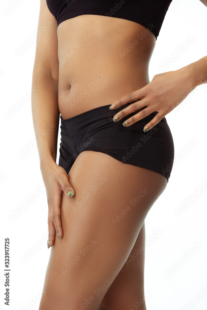 Anti-cellulite and epilation. Slim tanned woman's body on white studio background. African-american model with well-kept shape and skin. Beauty, self-care, weight loss, fitness, slimming concept.