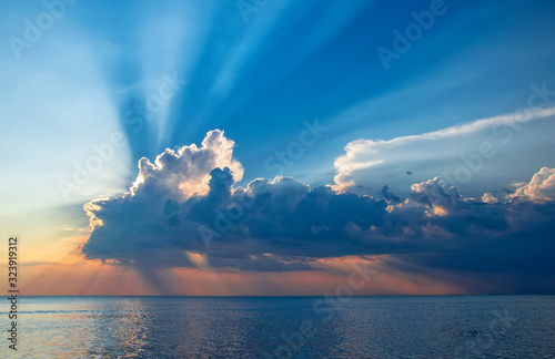 Fototapeta Naklejka Na Ścianę i Meble -  Magnificent sunset over sea. Sun covered by picturesque cloud with beautiful shine sun beams in sky