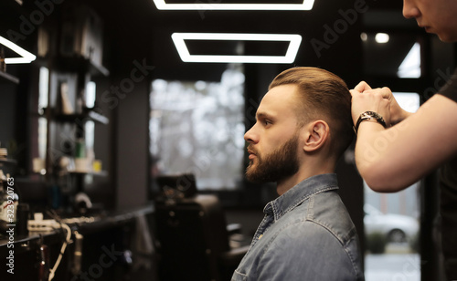 Ready for a new day. Close up side view photo of a young confident man looking in the mirror while having his hair done in a barbershop.
