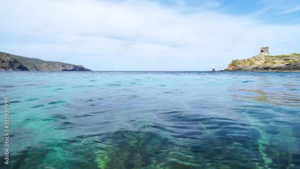 Wide-angle shot of a lighthouse and Venetian ruins in Andros Chora, looking out over the beautiful Aeagean Sea and it's crystal-clear, turquois water. Wide-angle shot of a lighthouse and Venetian ruins in Andros Chora, looking out over the beautiful Aeagean Sea and it's crystal-clear, turquois water.