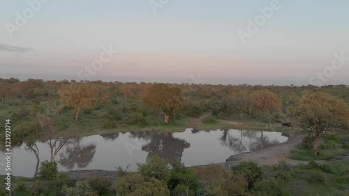 Aerial push-out shot of lake in South Africa as safari vehicle drives beside it photo