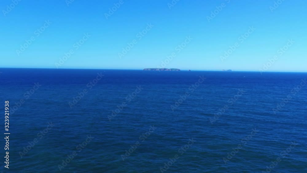 Zoom in to small island in the middle of calm, blue sea Zoom in to small island in the middle of calm, blue sea