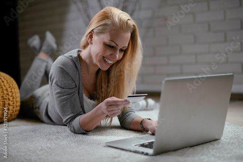 Girl is online shopping at home. Young woman holding credit card and using laptop computer. Online shopping concept 