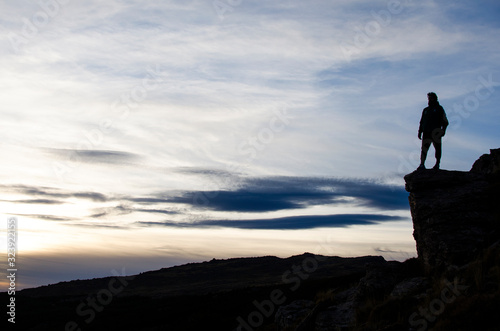 Liberty sensation. Man standing on the edge of a precipice facing a mountain landscape at sunset photo