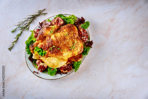 Traditional whole roasted chicken on plate with pomegranate, rosemary and green salad.
