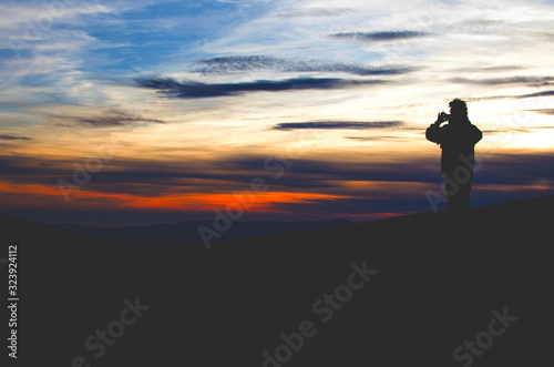 man on top making a photo of mountain landscape at sunset