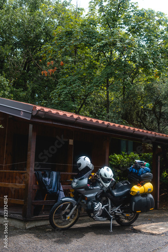 A small wooden house, a hotel room at the campsite. Touristic motorcycle with luggage. Travel and overnight concept on a motorbike ride