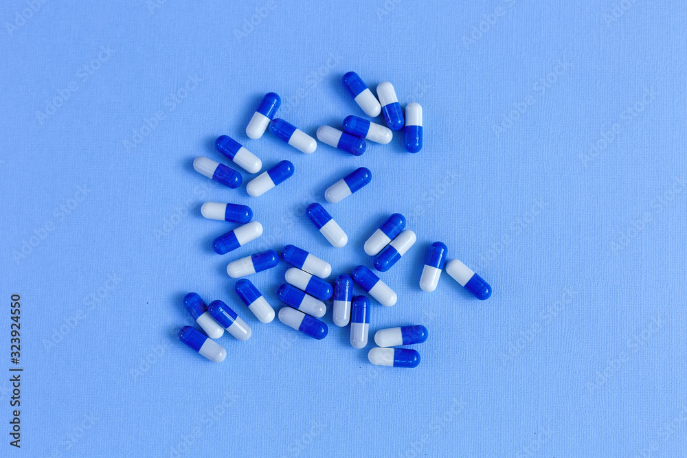 Medicinal capsules of white and blue color on the background. Medicinal capsules of white and blue color on the background.