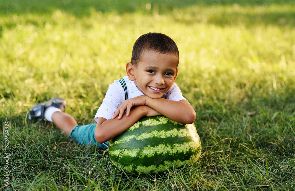 baby-cute black African American boy lying on a huge watermelon and smiling on a Park background on a Sunny summer day baby-cute black African American boy lying on a huge watermelon and smiling on a Park background on a Sunny summer day