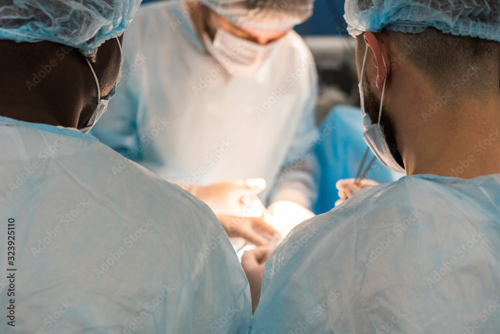 An international team of doctors performs a complex surgical operation on a patient under anesthesia. Modern operating room and experienced surgeons save lives An international team of doctors performs a complex surgical operation on a patient under anesthesia. Modern operating room and experienced surgeons save lives