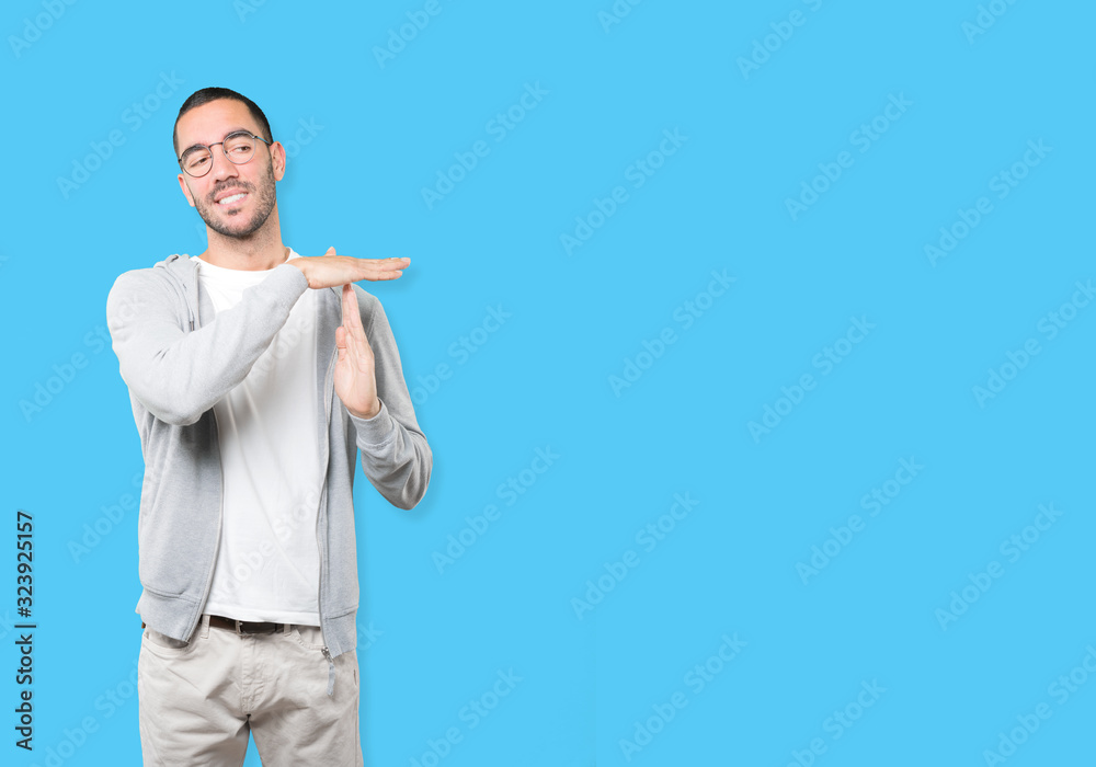 Stressed young man making a time out gesture with his hands Stressed young man making a time out gesture with his hands