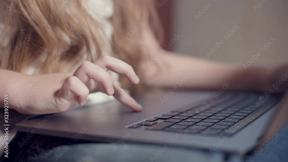 Closeup shallow depth of field of a little girl's hand on a laptop keyboard. The concept of using the younger generation of gadgets Closeup shallow depth of field of a little girl's hand on a laptop keyboard. The concept of using the younger generation of gadgets
