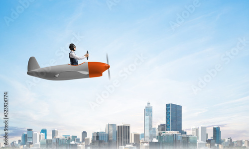 Businessman driving propeller plane above downtown