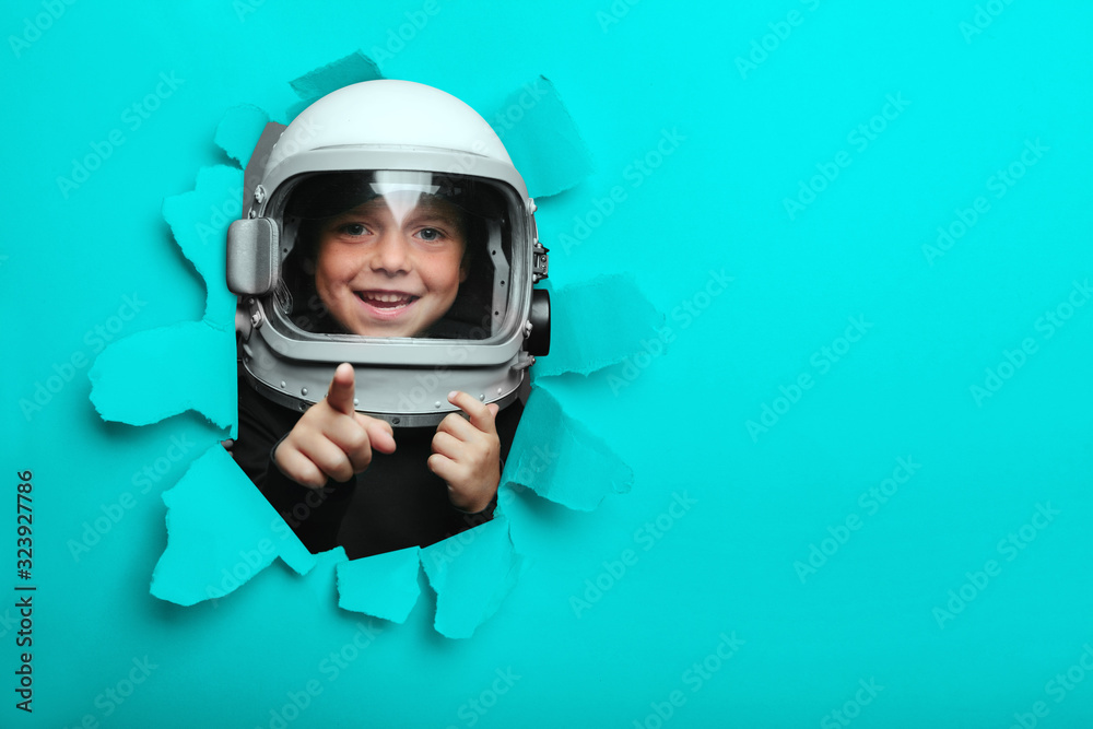Small child in wearing an airplane helmet looking through a hole of colored paper Small child in wearing an airplane helmet looking through a hole of colored paper