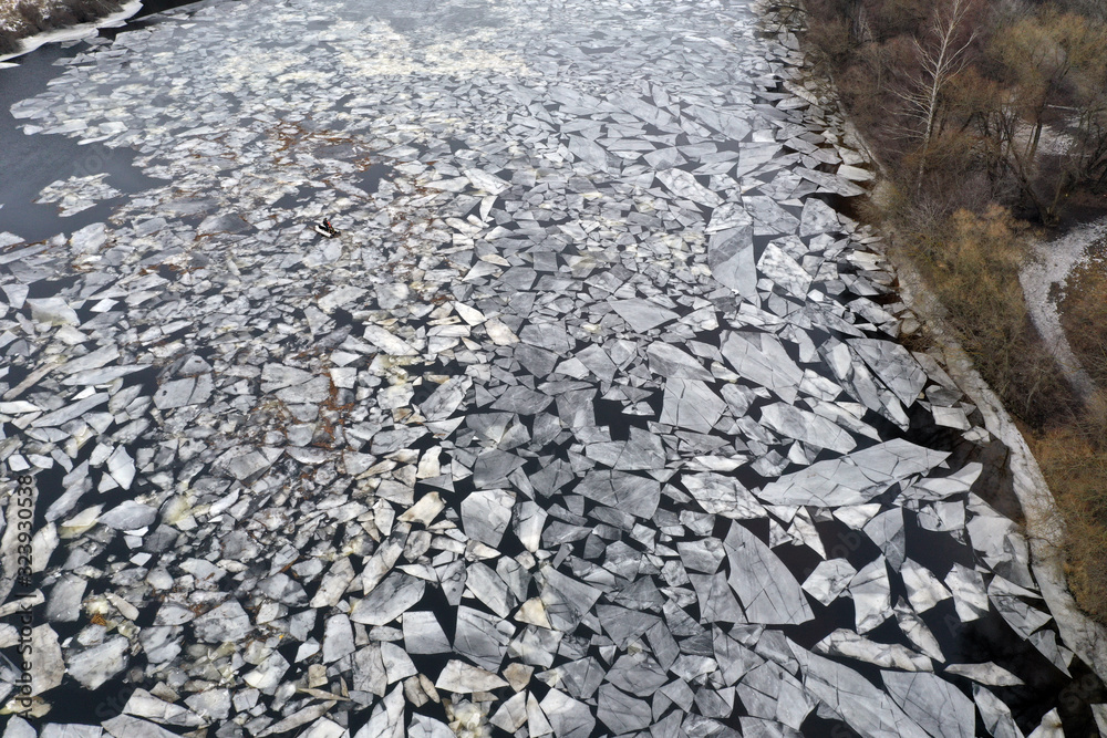 cracked ice on a dark river of unusual appearance
