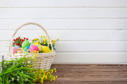 Canvas Print Colored easter eggs in the basket and spring flowers on wooden background