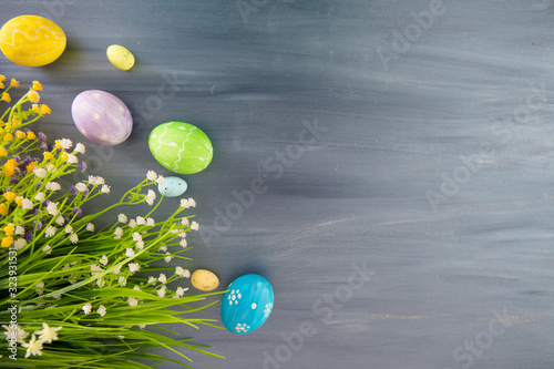 Easter eggs and flowers on gray wooden planks